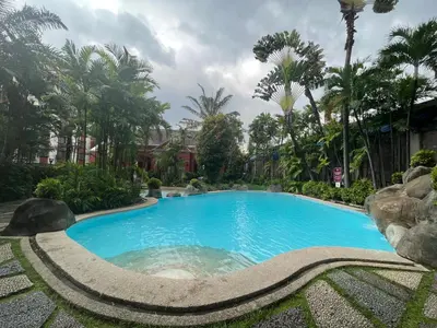 a swimming pool in a resort with palm trees at The Cozy Place Condo in Pasig Phil in Manila