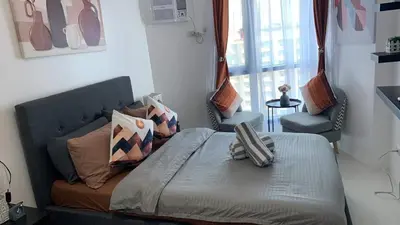 a bedroom with a bed with two chairs and a window at Comfy Condo Grand Riviera Suite, Roxas Blvd Ermita Manila infront of US Embassy in Manila