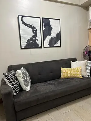 a black couch in a living room with two pictures at Cozy condo near Airport Manila in Manila