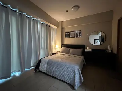 a bedroom with a bed and a mirror and curtains at Cozy condo near Airport Manila in Manila