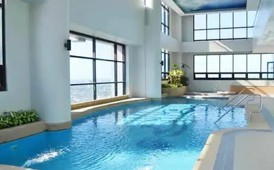 a large swimming pool with blue water in a building at Relaxing Big Studio Bedroom in Manila