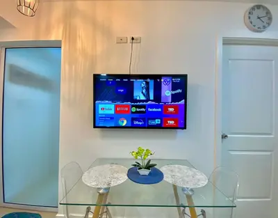 a dining room with a table and a tv on a wall at The Cozy-Corner Staycation at the Azure Urban Resort Residences in Manila