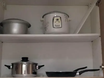 a pot and pans sitting on a shelf above a stove at 1 Bedroom lovely place near Mall of Asia in Manila