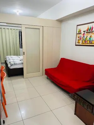a small room with a red couch and a bed at Destina Stays @Jazz Residences, Makati, Metro Manila, w/Netflix in Manila