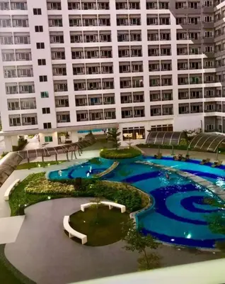 a large building with two pools in front of it at Affordable Fully Furnished Condo Unit in Manila