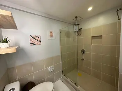 a bathroom with a toilet and a glass shower at Alea Residences in Manila