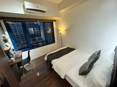 a bedroom with a bed and a desk and a window at Modern Classic 1 BR Condo Air Residences Makati in Manila