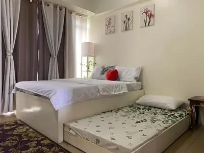 a bedroom with a bed and a bench in it at Staycation @150 Newport pasay city in Manila
