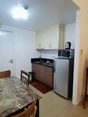 a kitchen with a table and a stainless steel refrigerator at Staycation @150 Newport pasay city in Manila