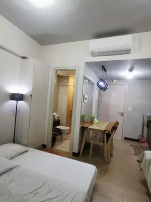 a bedroom with a bed and a table and a bathroom at Staycation @150 Newport pasay city in Manila