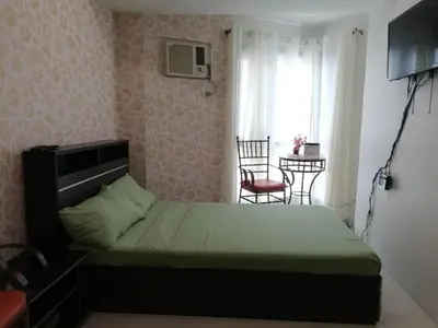 a bedroom with a bed and a table and a window at Grand riviera suites Studio Type Only in Manila