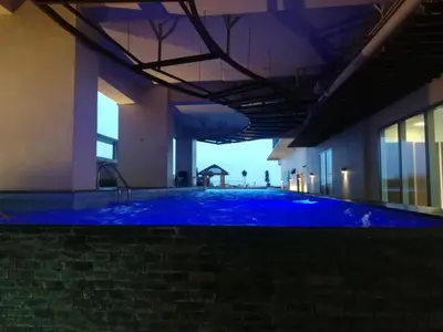a large swimming pool with blue water in a building at Grand riviera suites Studio Type Only in Manila