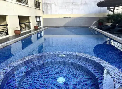 a large blue swimming pool in a building at Poolview Family Room Greenbelt Makati in Manila
