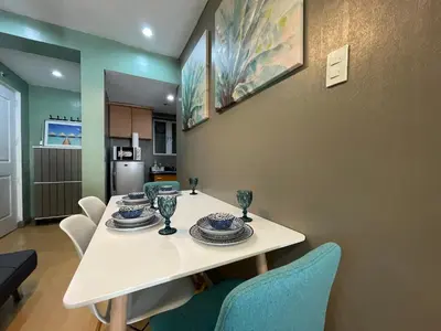 a dining room with a white table and chairs at Poolview Family Room Greenbelt Makati in Manila