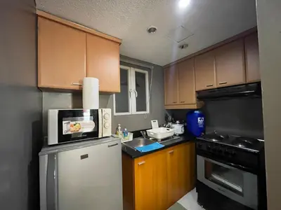 a kitchen with wooden cabinets and a white refrigerator at Poolview Family Room Greenbelt Makati in Manila