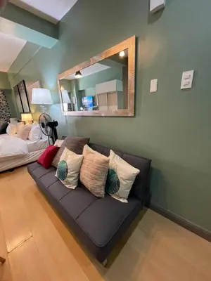 a couch with pillows in a room with a mirror at Poolview Family Room Greenbelt Makati in Manila