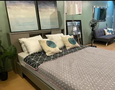 a bedroom with a bed with pillows and a tv at Poolview Family Room Greenbelt Makati in Manila