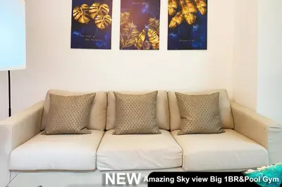 a white couch in a living room with three paintings at Century Spire Makati in Manila