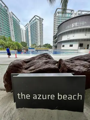 a sign that reads the zire beach with buildings in the background at The Carribean Suites by Azure in Manila