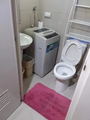 a bathroom with a toilet and a sink and a pink rug at Condo at Shell Residences in Manila