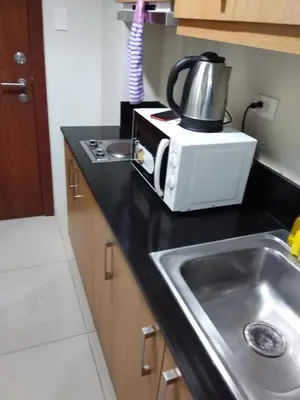 a kitchen counter with a sink and a microwave at Condo at Shell Residences in Manila