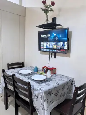 a dining room table with chairs and a tv on the wall at Sea Residences Tower F in Manila