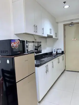 a kitchen with white cabinets and a black microwave at Sea Residences Tower F in Manila