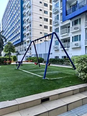 a swing set in a park with tall buildings at Sea Residences Tower F in Manila