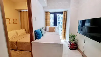 a small room with a bed and a television at Shore 3 Residences Mall of Asia Pool view Netflix free wifi in Manila