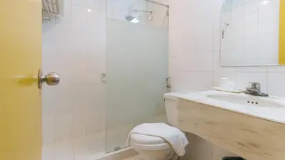 a white bathroom with a toilet and a sink at Aloha Hotel Roxas Boulevard Manila in Manila
