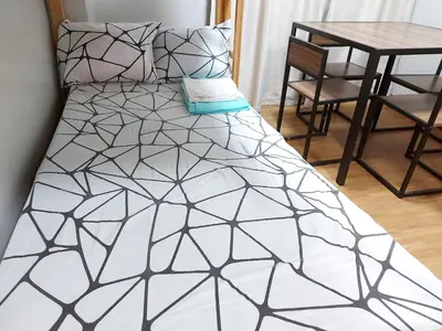 a bed with a black and white comforter and a table at Bunked Bed Room Sharing in Manila