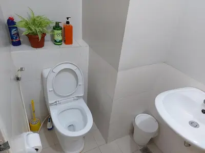 a white bathroom with a toilet and a sink at Bunked Bed Room Sharing in Manila