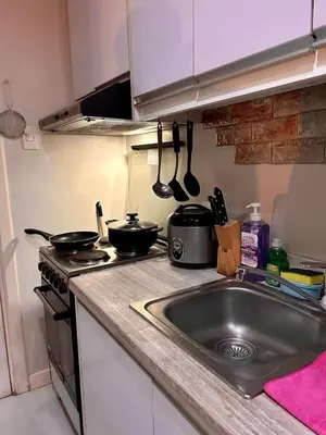 a kitchen with a sink and a stove with pots and pans at 22-A Cozy condo in KL Mosaic Residences near Greenbelt with free WIFI in Manila