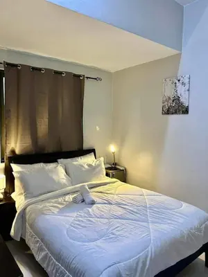a bedroom with a large white bed with white pillows at 22-A Cozy condo in KL Mosaic Residences near Greenbelt with free WIFI in Manila