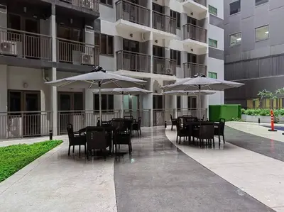 a patio with tables and chairs with umbrellas in a building at MoA S Residences Family Suite with balcony in Manila