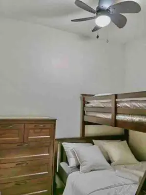 a bedroom with a bed with a ceiling fan and a dresser at MoA S Residences Family Suite with balcony in Manila