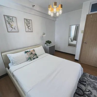 a bedroom with a large white bed and a mirror at Lancris Residences 2 Bedroom Entire Apartment near Airport with Pool in Manila