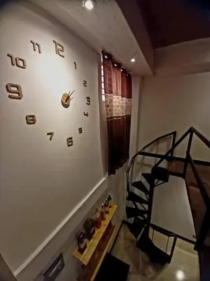 a room with a clock on the wall and a staircase at Adorable Lounge - 1 Bedroom loft w/home cinema in Manila