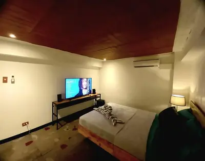 a bedroom with a bed and a flat screen tv at Adorable Lounge - 1 Bedroom loft w/home cinema in Manila