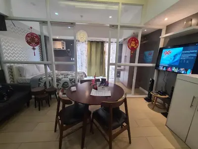 a living room with a table and a bedroom at Venice Luxury Residences in Manila