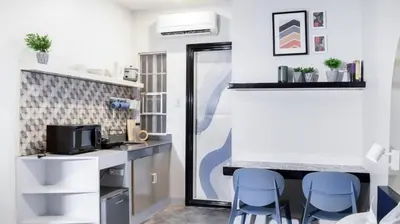 a small kitchen with two blue chairs in a room at Hive Manila Guesthouse and Apartments 400 Mbps - Gallery Studio in Bacoor