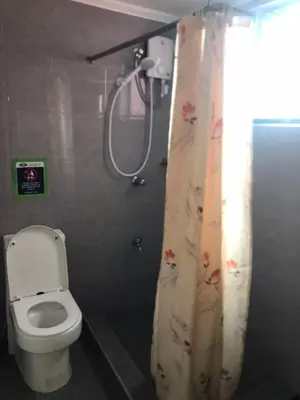 a bathroom with a toilet and a shower curtain at Alta Vitas Daily in Manila