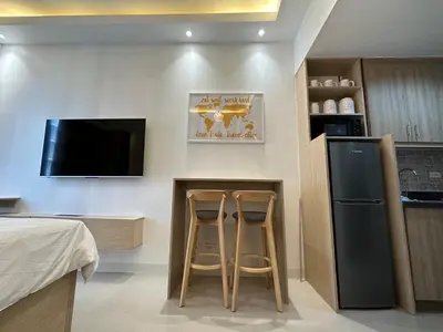 a kitchen with two stools and a counter with a refrigerator at Homey Condo by the Bay in Manila