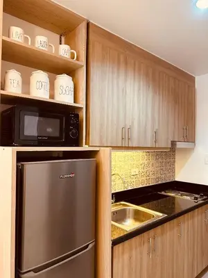 a kitchen with wooden cabinets and a stainless steel refrigerator at Homey Condo by the Bay in Manila