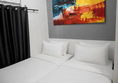 a bed with white sheets and a painting on the wall at mySTAY Hotel BGC South in Manila