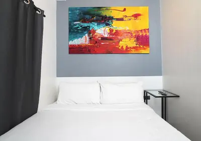 a bedroom with a bed and a painting on the wall at mySTAY Hotel BGC South in Manila
