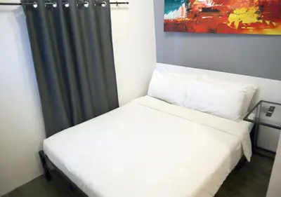 a bedroom with a white bed with a shower curtain at mySTAY Hotel BGC South in Manila