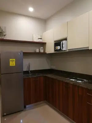 a kitchen with a stainless steel refrigerator and wooden cabinets at Adria Residences - Sapphire Garden - 2 Bedroom for 4 person in Manila