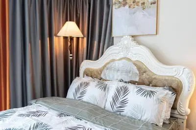 a bedroom with a white bed with pillows and a lamp at A2J Luxury 2BR BGC Uptown Suite Near Uptown Mall in Manila