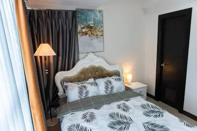 a bedroom with a bed and a lamp and a window at A2J Luxury 2BR BGC Uptown Suite Near Uptown Mall in Manila